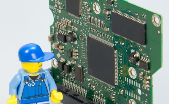 Płytka elektroniczna ze stojącym obok ludzikiem LEGO w stroju elektryka